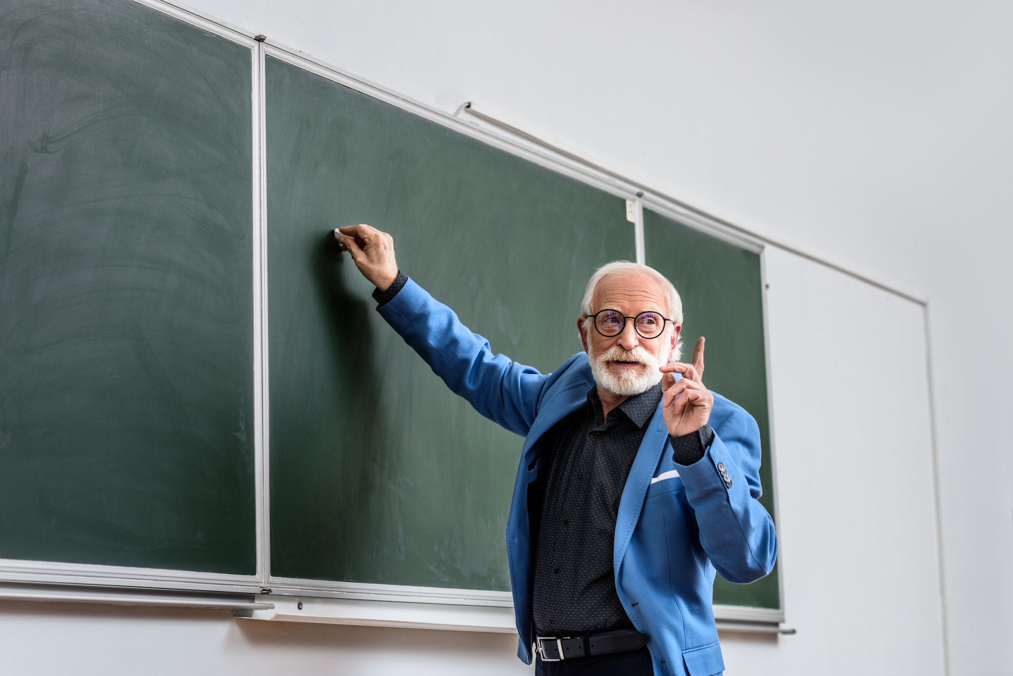 senior-lecturer-writing-something-on-blackboard-and-showing-one-finger-up.jpg